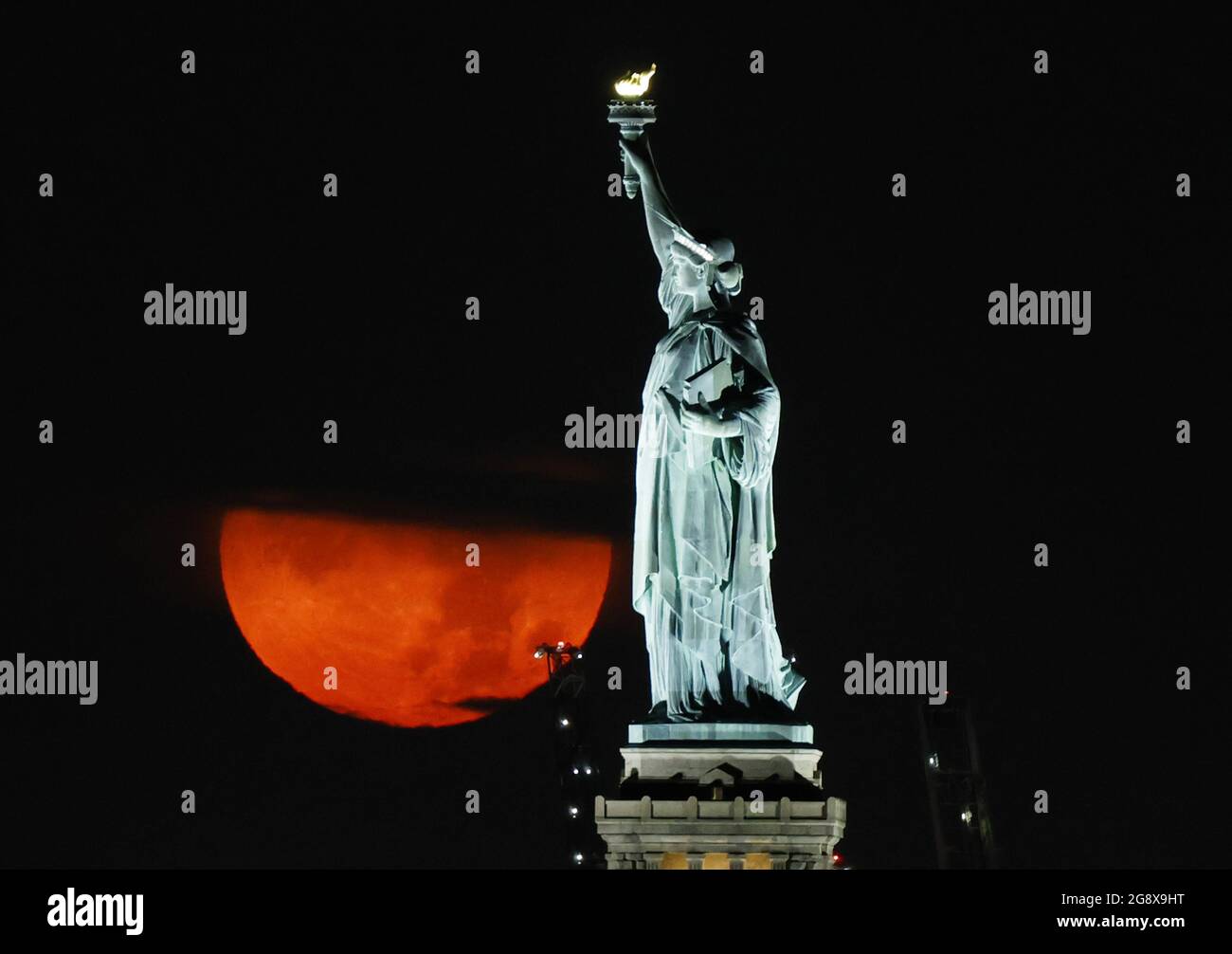 New York, États-Unis. 23 juillet 2021. Une pleine Buck Moon, partiellement obstruée par des nuages, se pose derrière la Statue de la liberté à New York le vendredi 23 juillet 2021. Photo de John Angelillo/UPI crédit: UPI/Alay Live News Banque D'Images