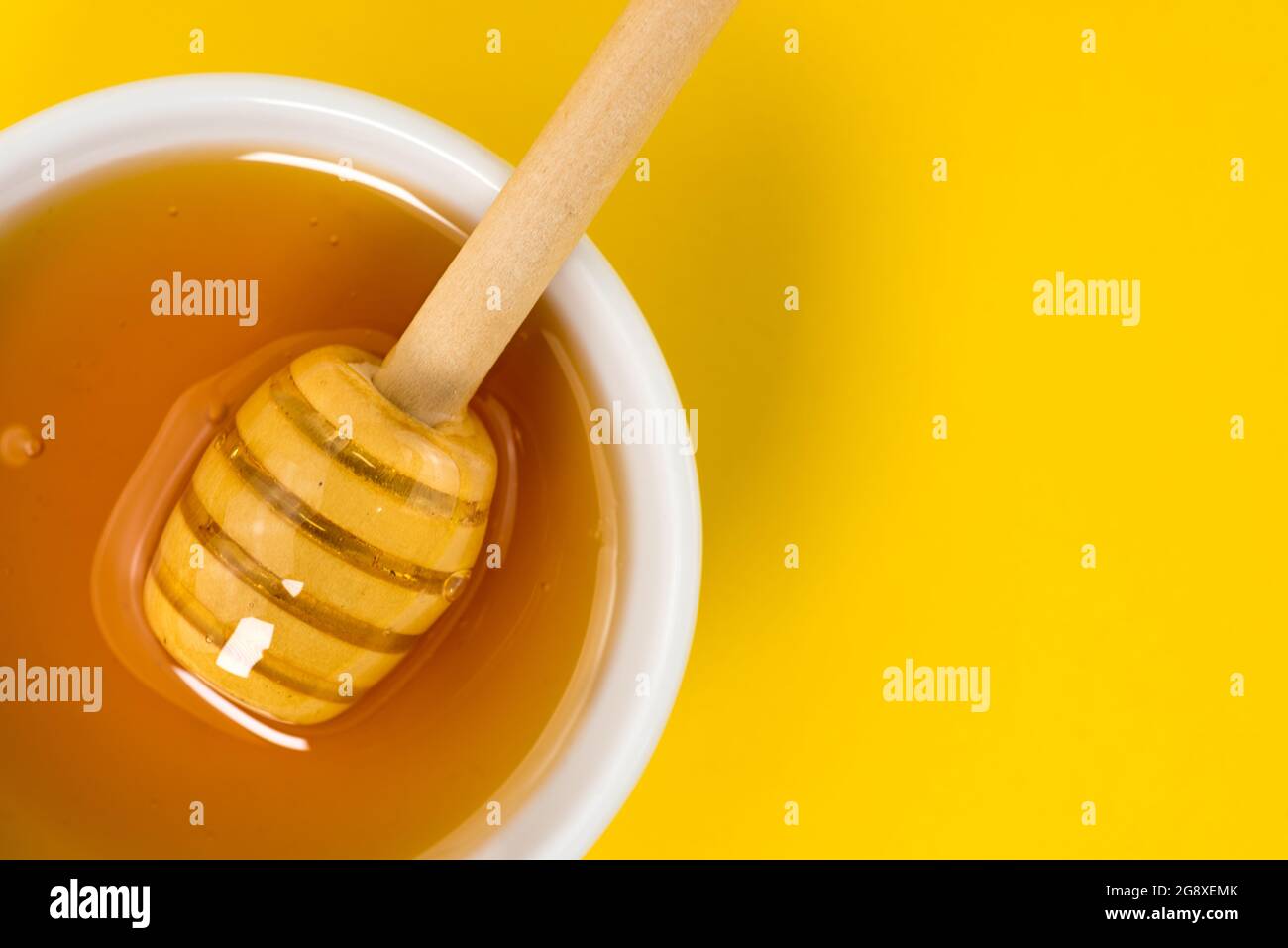 Gros plan de la louche de miel avec le miel de châtaignier isolé sur fond jaune, espace de copie Banque D'Images