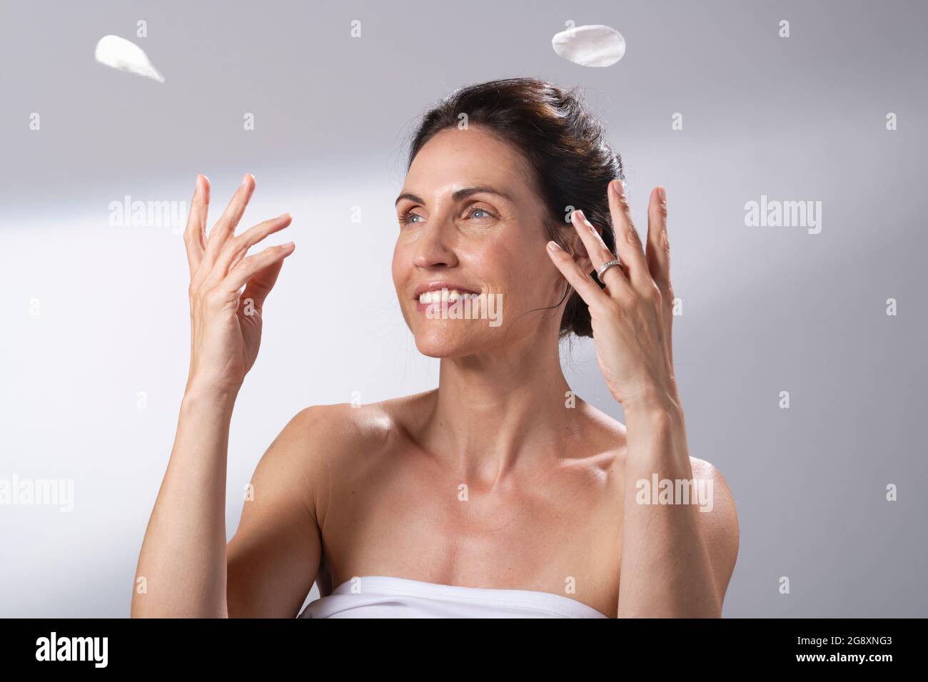 Une femme souriante s'amusant avec une paire de tampons de coton. Une femme les jette. Banque D'Images