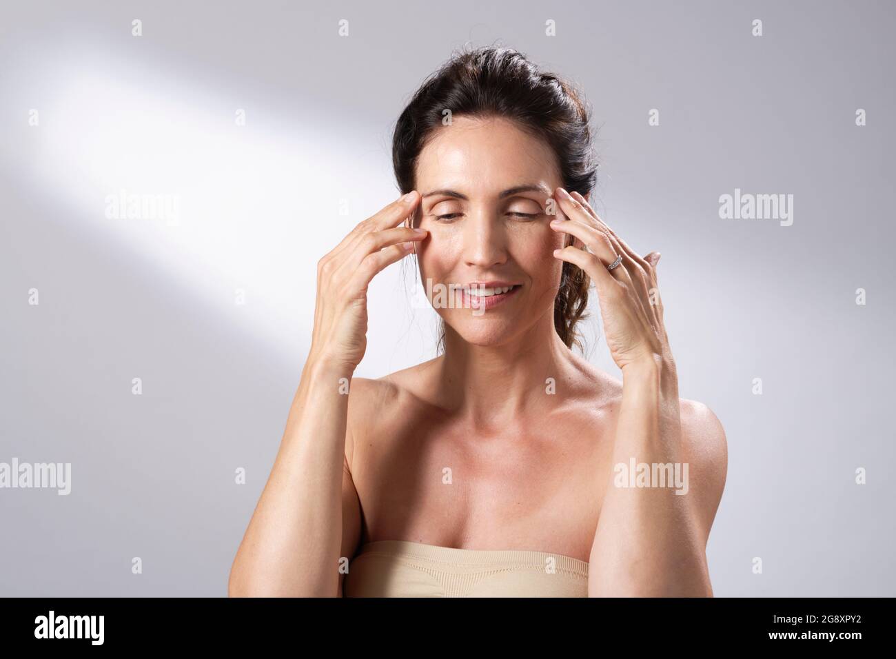 Un régime de soin de la peau de femme. Mains et doigts sur le visage et massage doux. Banque D'Images