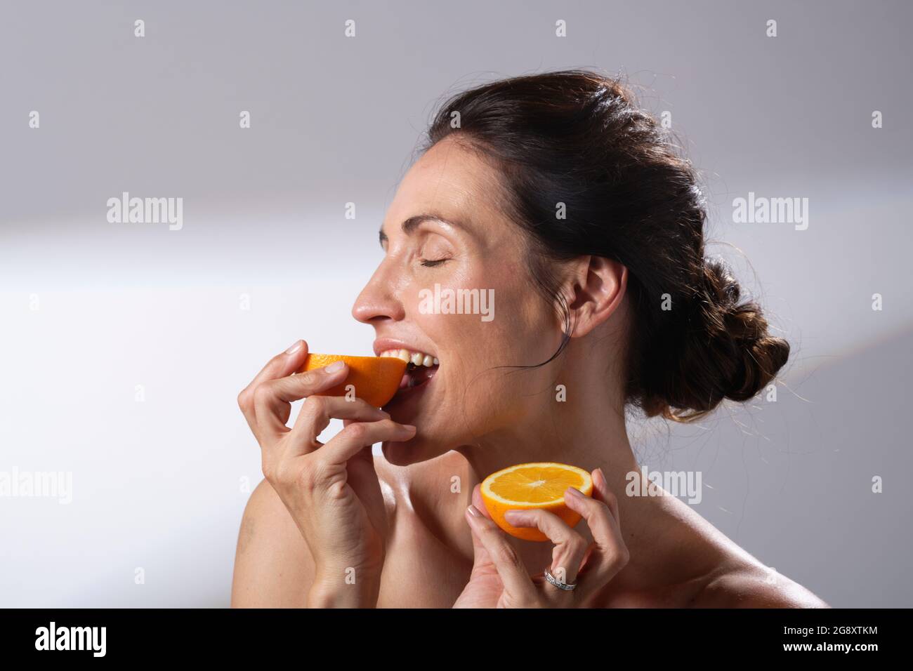 Une femme tenant un fruit orange frais dans ses mains. Deux moitiés d'une orange. Banque D'Images