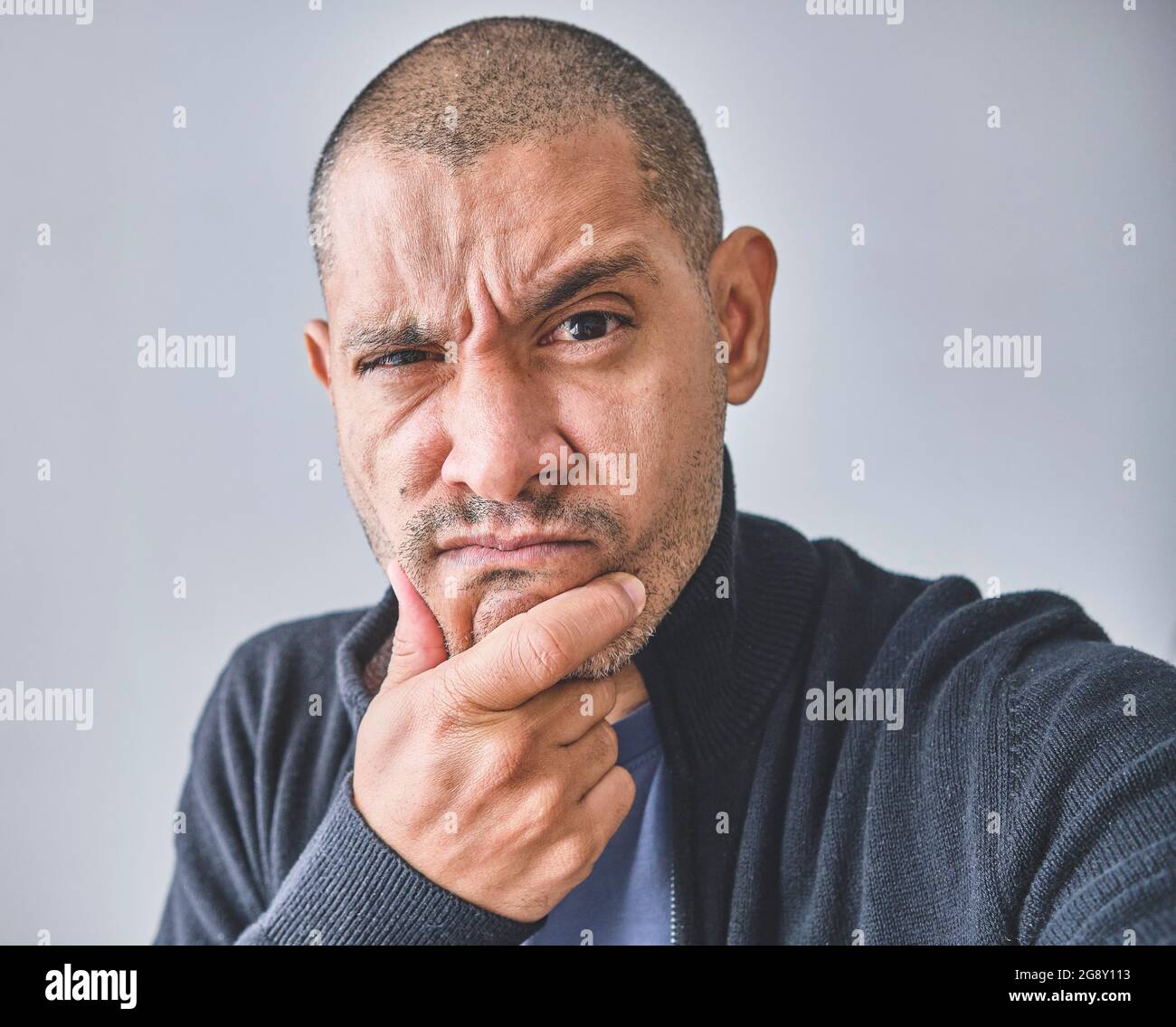 Homme d'âge moyen avec main sur le menton question de pensée, expression pensive. Sourire avec visage réfléchi. Doute concept. Isolé sur le mur blanc du studio. Banque D'Images