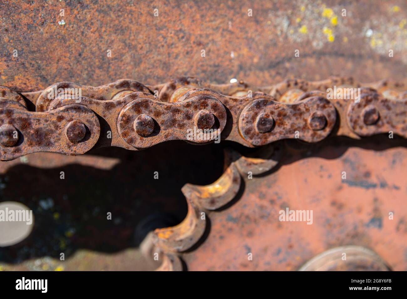 Détails rouillés des vieilles voitures abandonnées. Les pignons, les chaînes et les poulies rouillent dans l'ouverture. Pièces métalliques recouvertes de mousse de machines agricoles. Banque D'Images