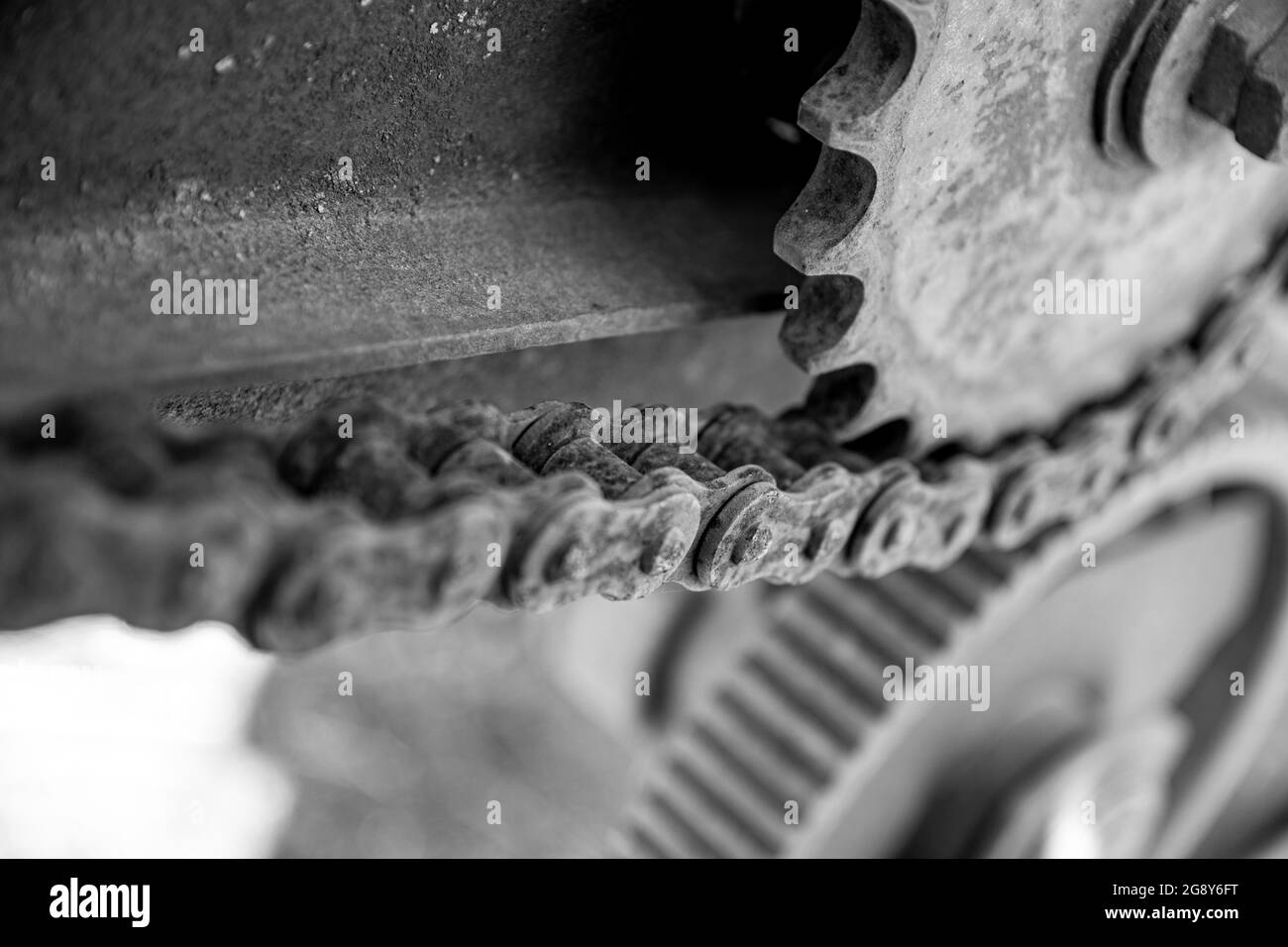 Détails rouillés des vieilles voitures abandonnées. Les pignons, les chaînes et les poulies rouillent dans l'ouverture. Pièces métalliques recouvertes de mousse de machines agricoles. Imag noir et blanc Banque D'Images