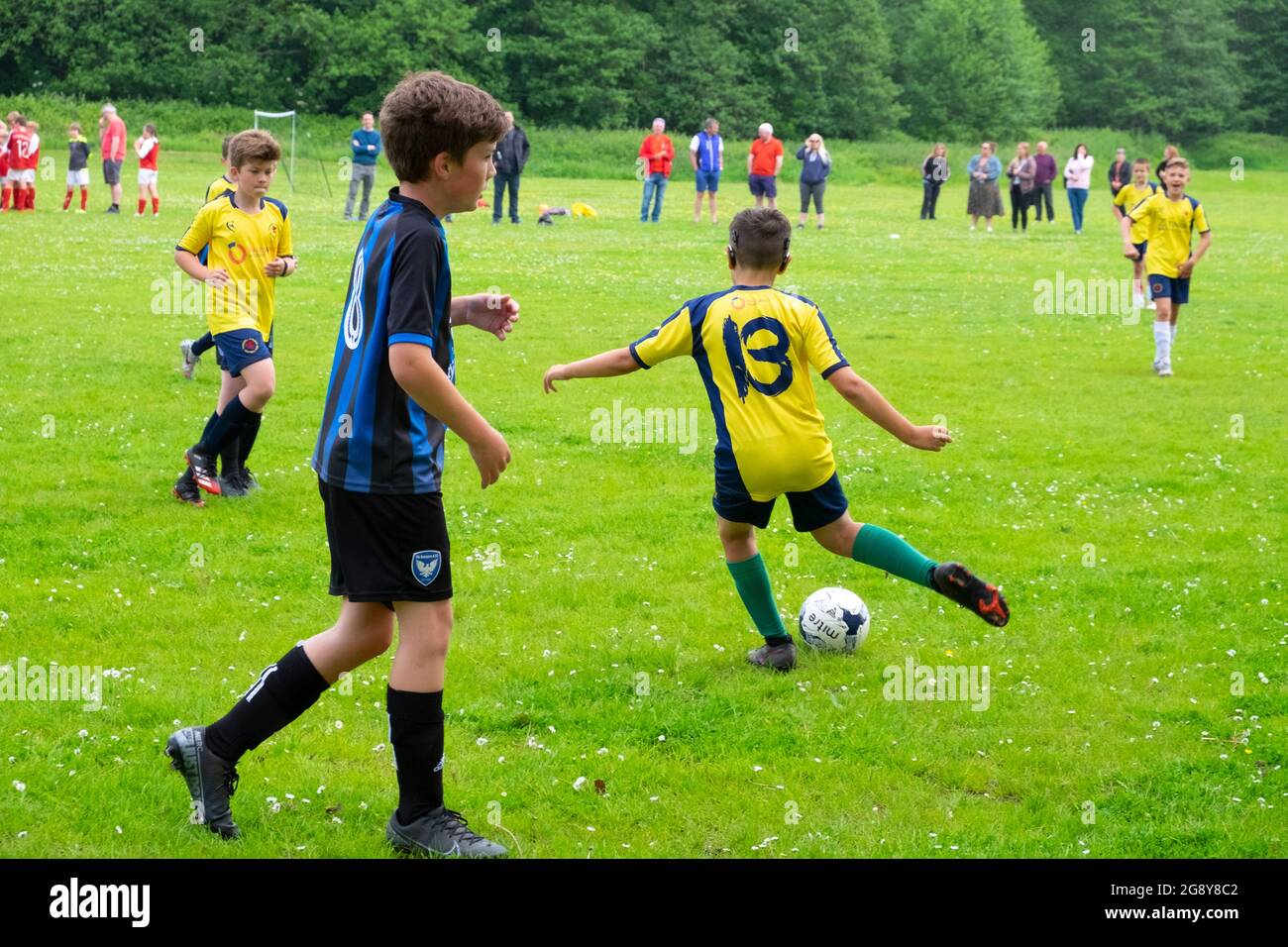 Arrière joueur de l'équipe de garçon kick kicks kicking ball les équipes de garçons jouent au football le samedi matin au Royaume-Uni Grande-Bretagne 2021 KATHY DEWITT Banque D'Images
