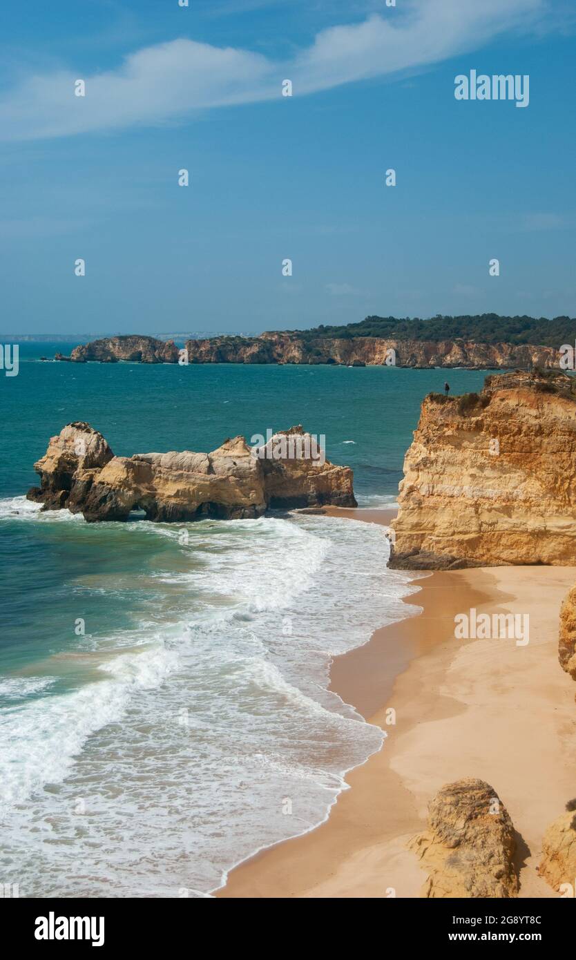 Vue verticale de la belle plage avec des falaises et de longues vagues, ciel bleu avec des nuages rares, eau bleu profond - espace pour le texte Banque D'Images