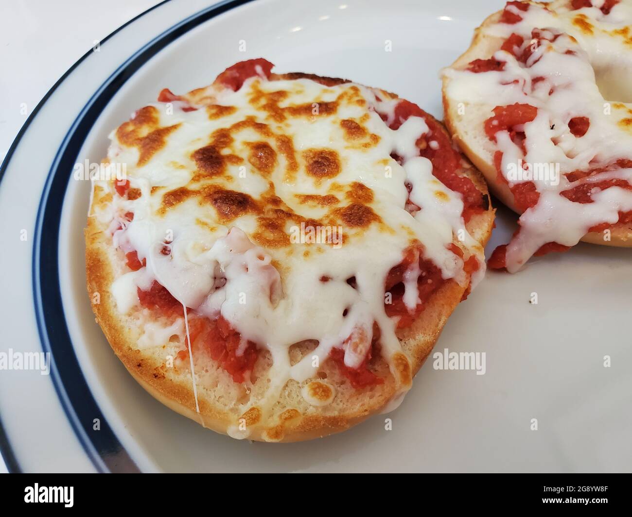 ÉTATS-UNIS. 20 avril 2021. Gros plan en grand angle de deux moitiés de bagel à pizza, reposant sur une assiette à rebord bleu, photographiée à Lafayette, Californie, le 20 avril 2021. (Photo par Smith Collection/Gado/Sipa USA) crédit: SIPA USA/Alay Live News Banque D'Images