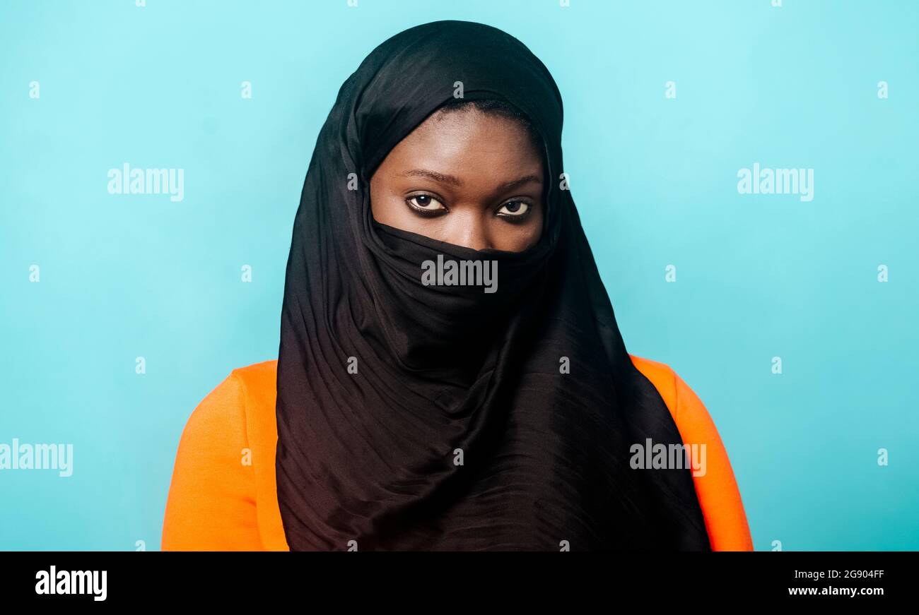 Jeune femme portant le hijab debout sur fond bleu Banque D'Images