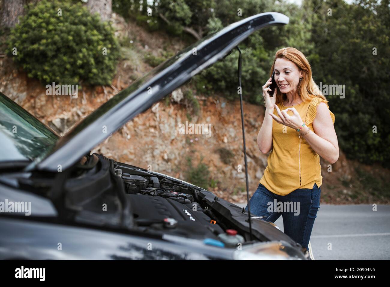 Femme parlant au téléphone mobile pour l'assistance routière en voiture Banque D'Images