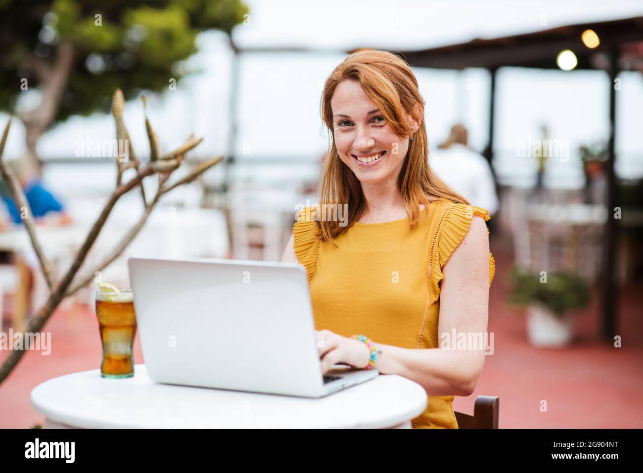 Femme indépendante assise avec un ordinateur portable et un verre au bar Banque D'Images