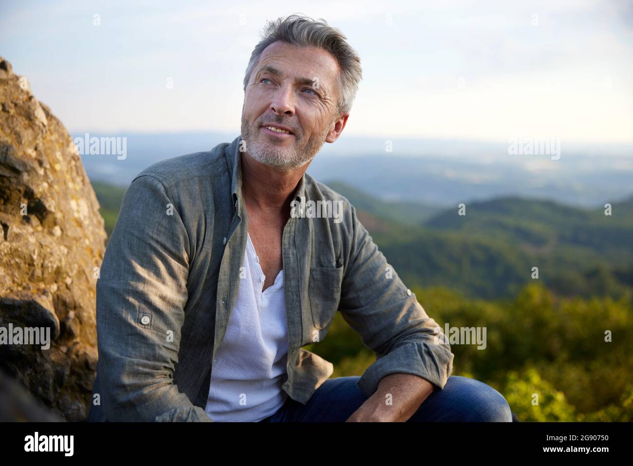 Un randonneur masculin attentionné qui regarde loin en étant assis sur la montagne Banque D'Images