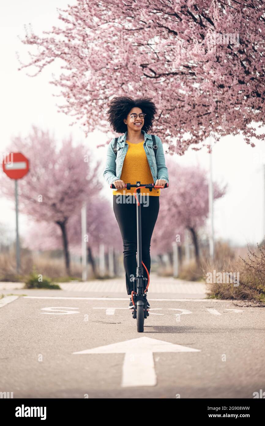 Femme souriante à bord d'un scooter électrique Banque D'Images