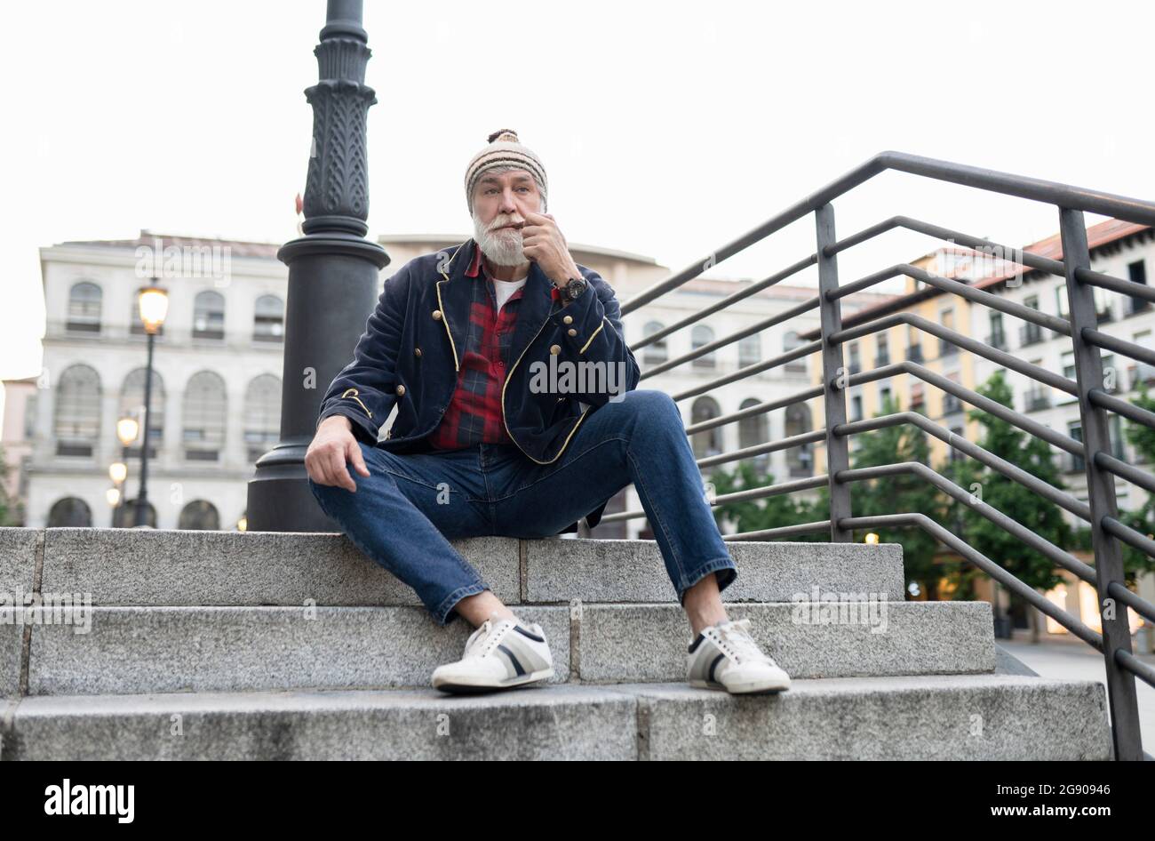 Homme mûr regardant loin en fumant un tuyau sur les marches Banque D'Images