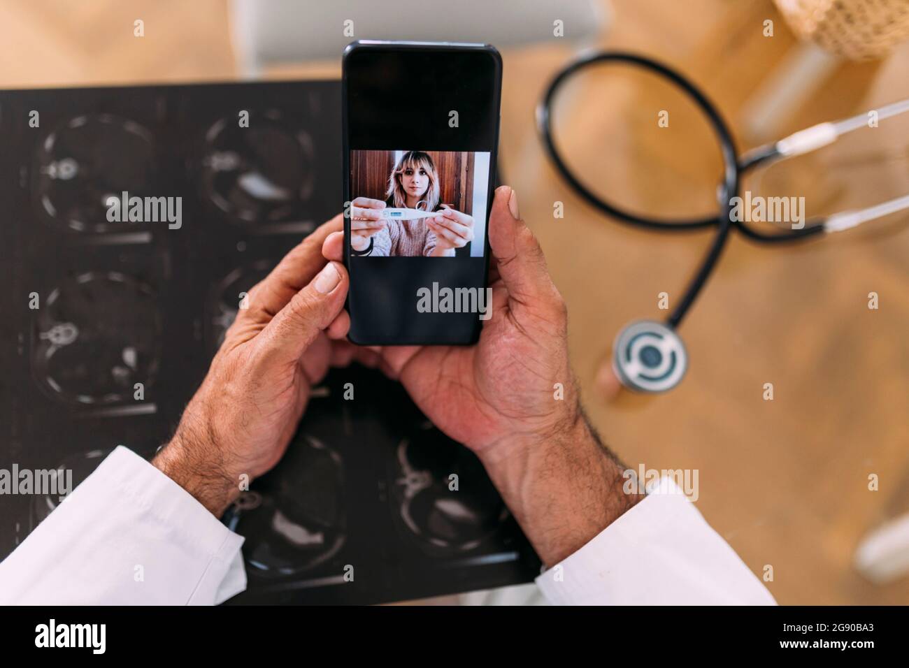 Patiente montrant un thermomètre à un médecin pendant un appel vidéo en clinique Banque D'Images