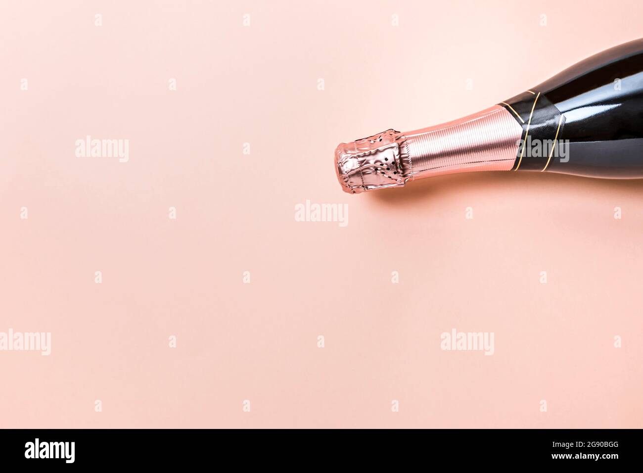 Studio avec une bouteille de champagne sur fond rose pastel Banque D'Images