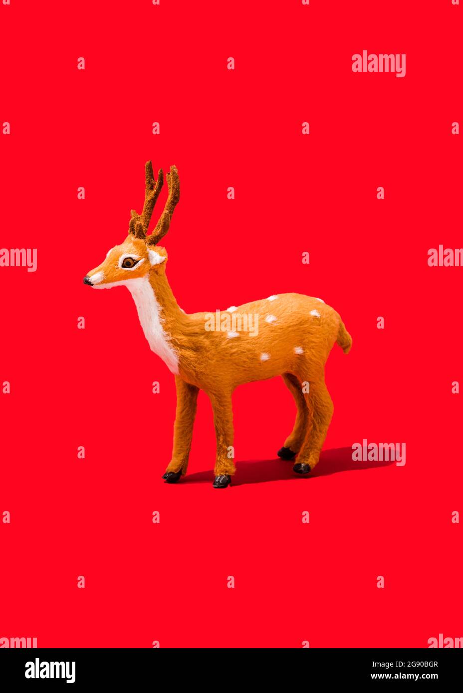 Photo de studio de figurine de renne debout sur fond rouge vif Banque D'Images