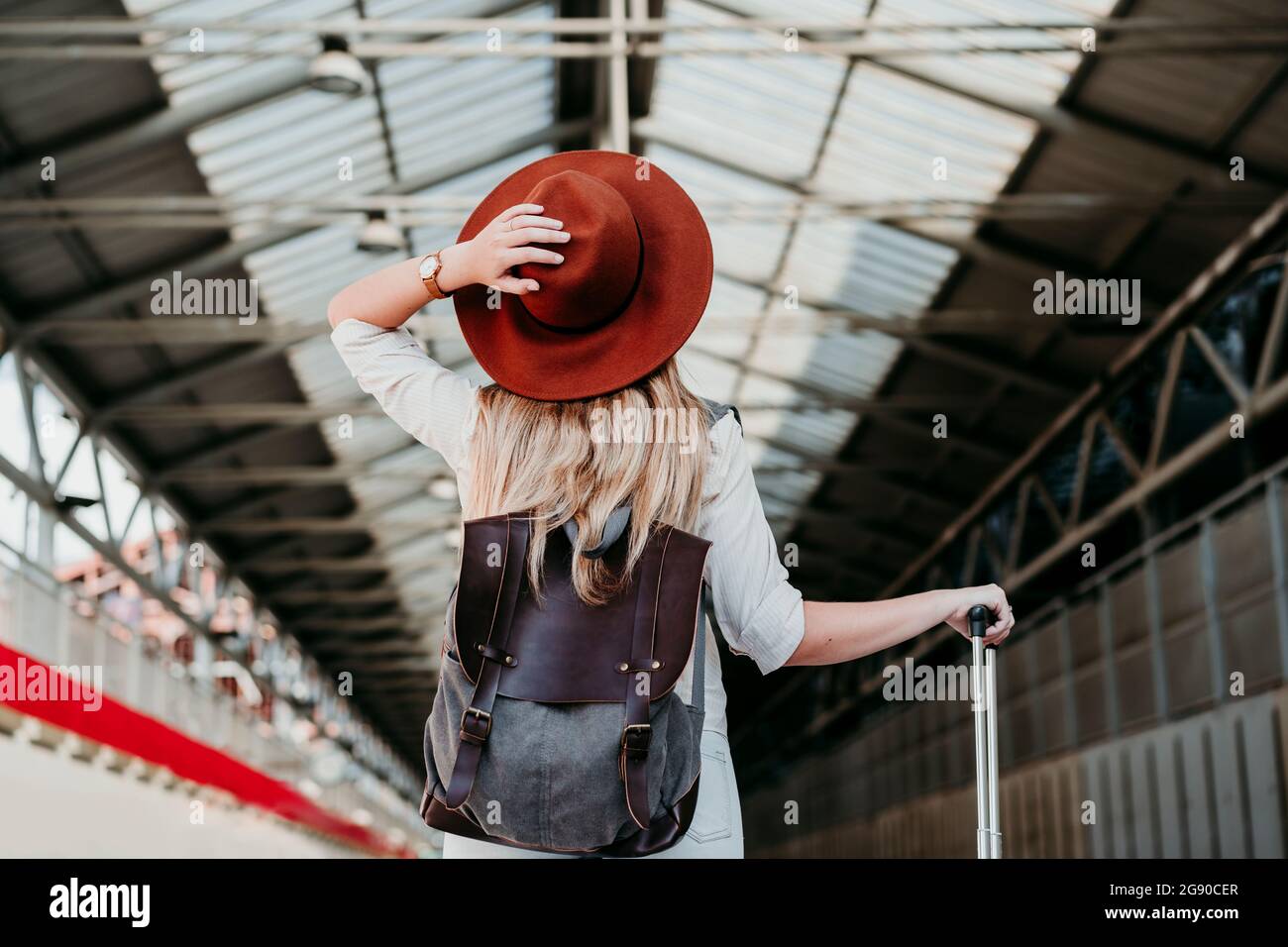 Jeune femme blonde portant un chapeau rouge à la gare Banque D'Images