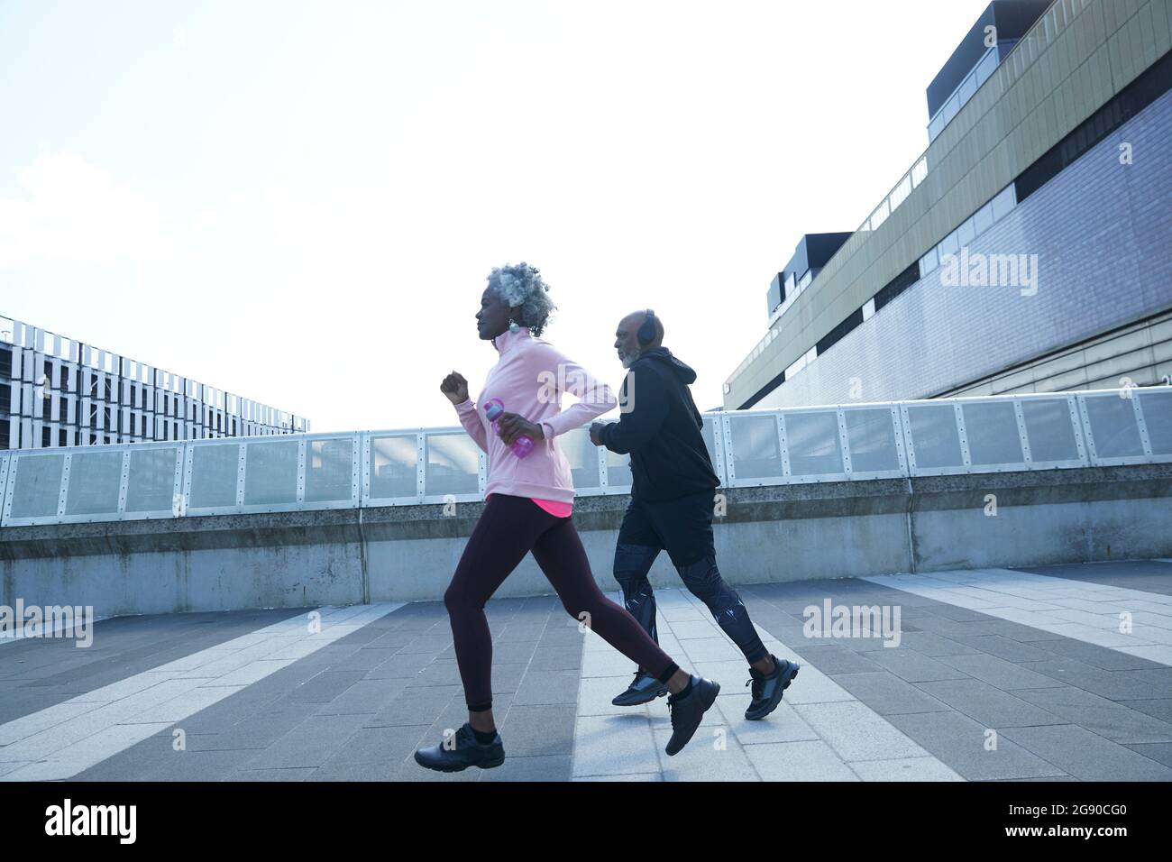 Femme âgée qui court avec un homme sur une piste de marche Banque D'Images