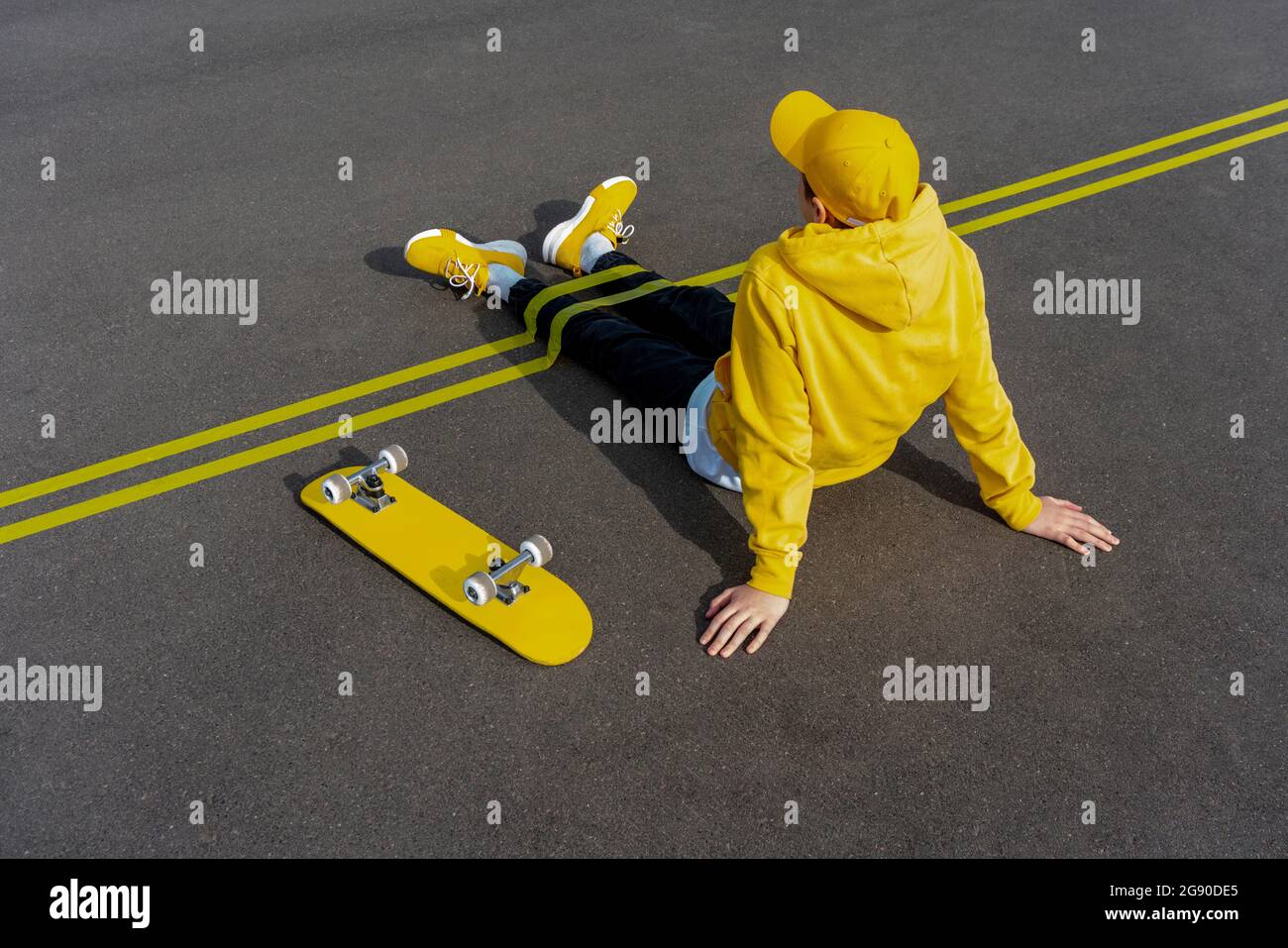 Rubans adhésifs jaunes sur les jambes de garçon par planche à roulettes sur la route Banque D'Images