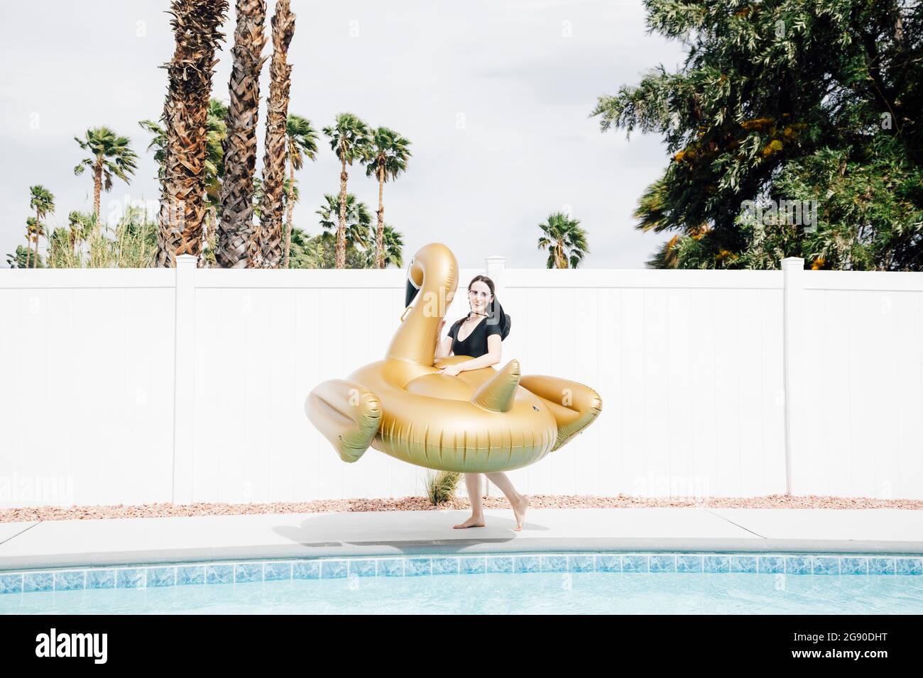 Femme tenant un cygne gonflable au bord de la piscine pendant la journée ensoleillée Banque D'Images