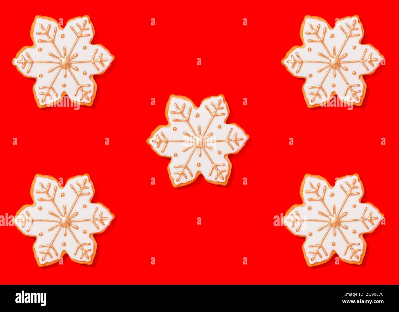 Cinq biscuits de Noël en forme de flocons de neige sur fond rouge vif Banque D'Images