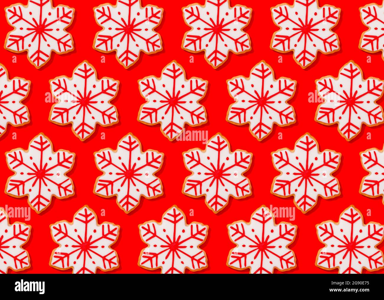 Motif de biscuits de Noël en forme de flocons de neige posé à plat sur fond rouge vif Banque D'Images