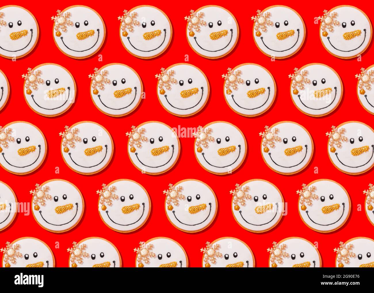 Motif de biscuits de Noël en forme de bonhomme de neige posé à plat sur fond rouge vif Banque D'Images