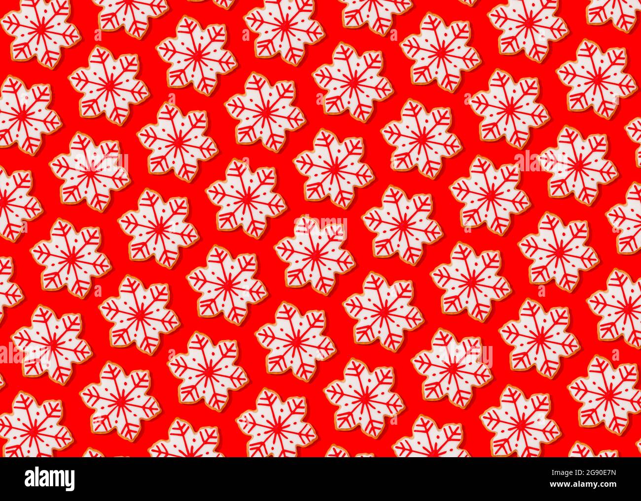 Motif de biscuits de Noël en forme de flocons de neige posé à plat sur fond rouge vif Banque D'Images