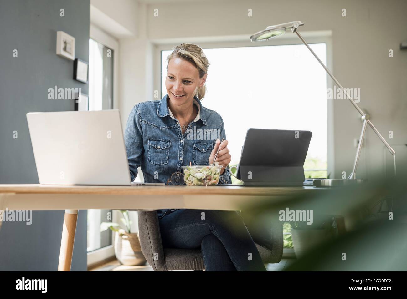 Employée indépendante utilisant un ordinateur portable lorsqu'elle est au bureau à domicile Banque D'Images