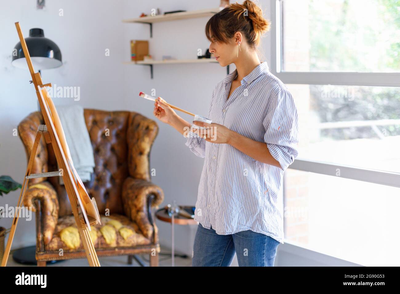 Jeune femme peintre regardant la peinture en studio Banque D'Images