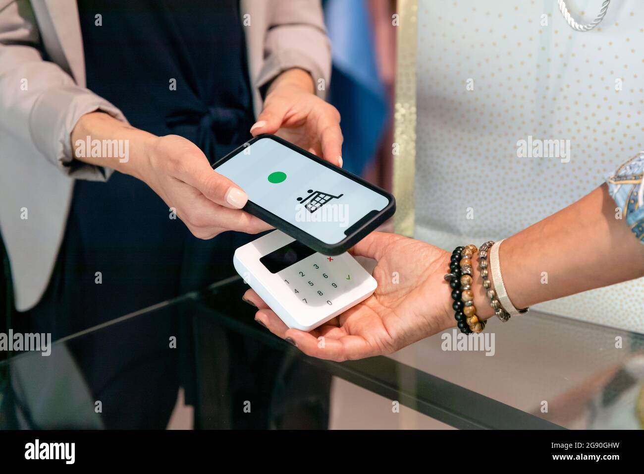 Femme qui fait le paiement par smartphone à la boutique de vêtements Banque D'Images