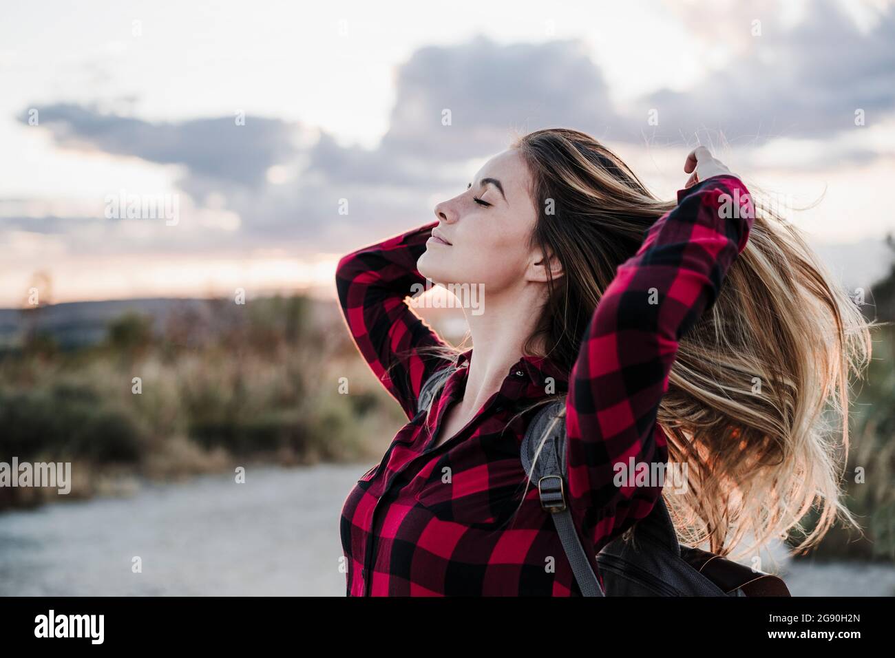 Belle jeune femme avec les yeux fermés les mains dans les cheveux Banque D'Images
