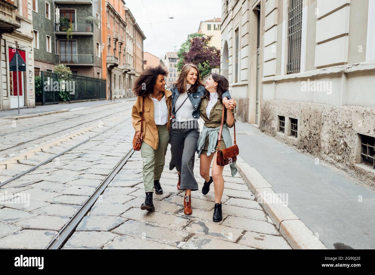 Femmes avec le bras autour de sourire en marchant au tramway Banque D'Images