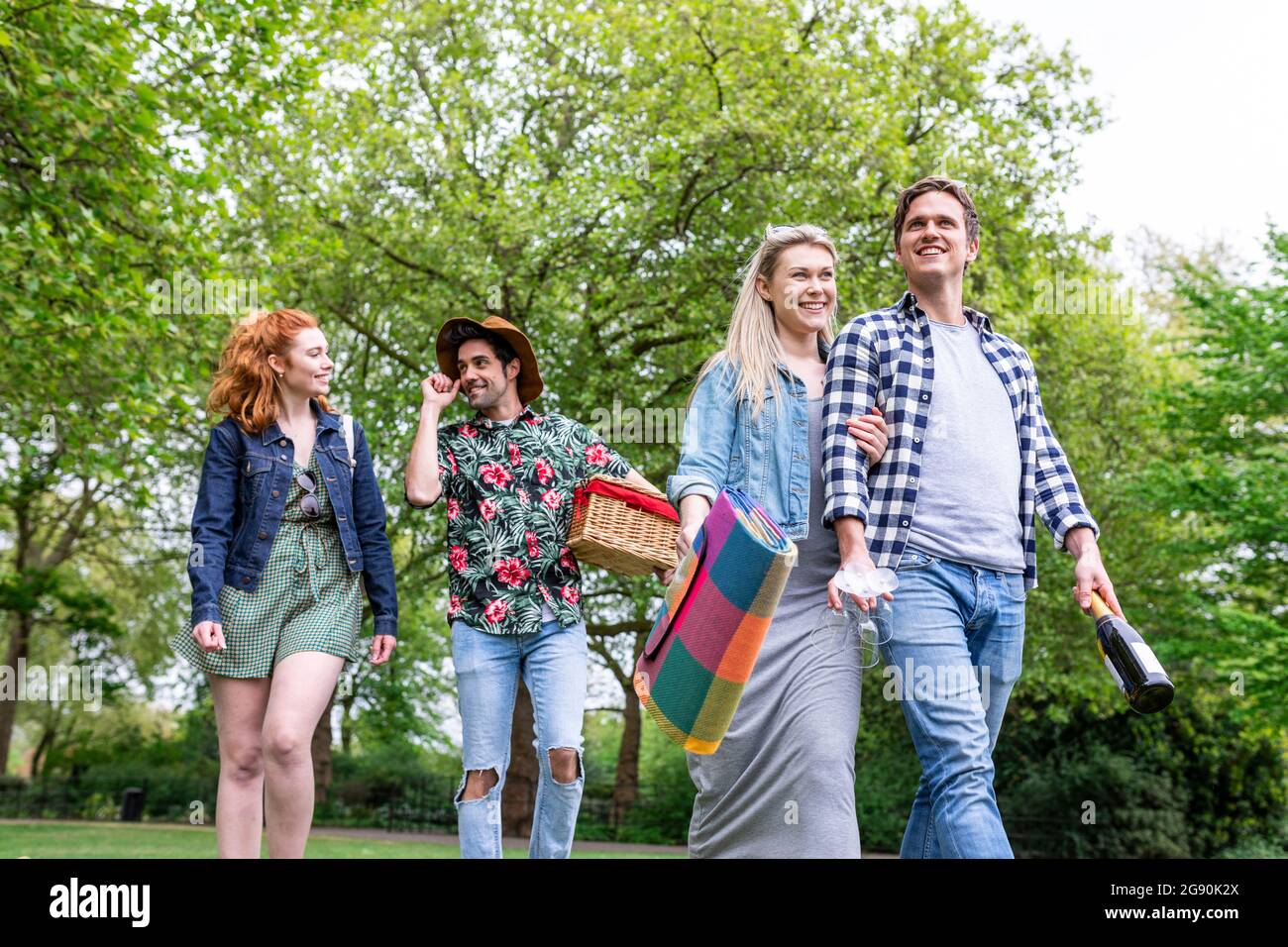 Des amis souriants, hommes et femmes, se promenant ensemble au parc Banque D'Images Des amis souriants, hommes et femmes, se promenant ensemble au parc Banque D'Images