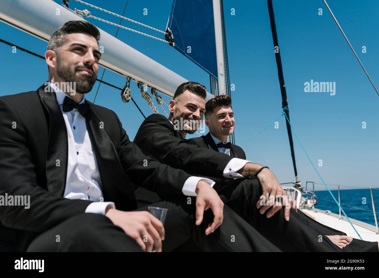 Beaux hommes regardant loin en voyageant en yacht pendant la journée ensoleillée Banque D'Images