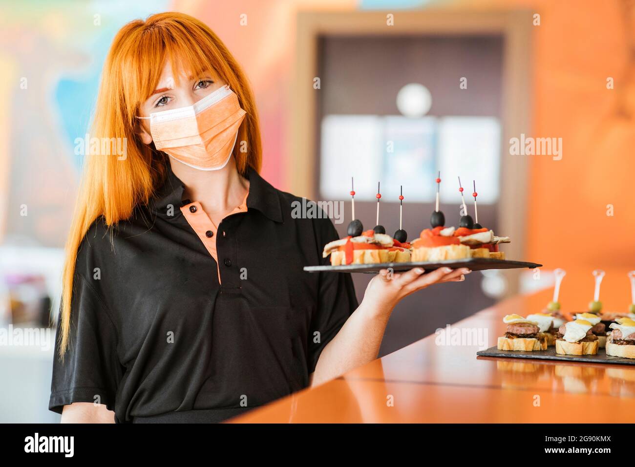Jeune serveuse à tête rouge tenant un conseil de service à la cafétéria Banque D'Images Jeune serveuse à tête rouge tenant un conseil de service à la cafétéria Banque D'Images