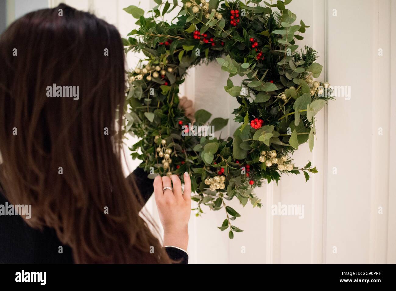 Brunette femme faisant une couronne de Noël avec houx, lierre et GUI Banque D'Images