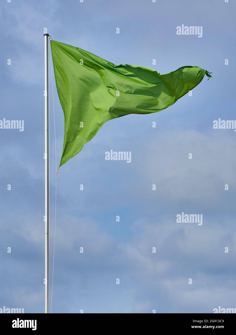 Un drapeau vert triangulaire sur un ciel nuageux. Banque D'Images