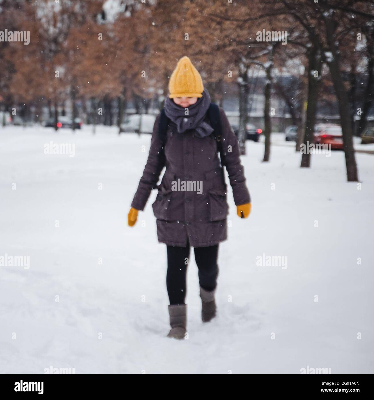 Bonne jeune femme européenne dans un bonnet tricoté jaune et des mitaines  avec un sac à dos, rit sous la neige. Effet rétro. Flou Photo Stock - Alamy