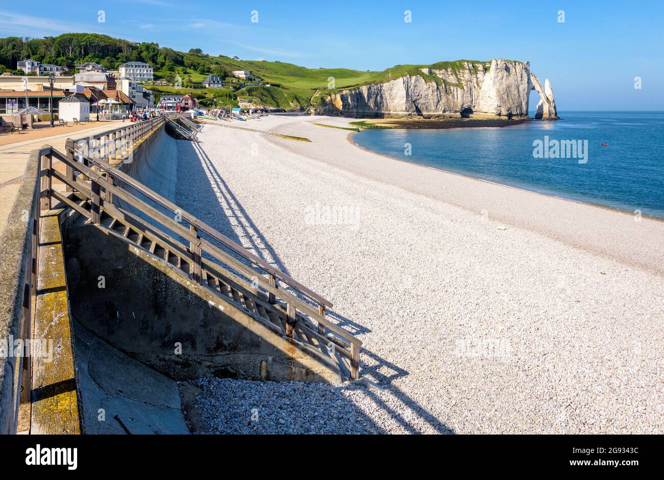 Le front de mer et la plage de galets d'Etretat en Normandie avec l'aiguille et l'arche de la falaise d'Aval au loin sur un matin ensoleillé de printemps. Banque D'Images