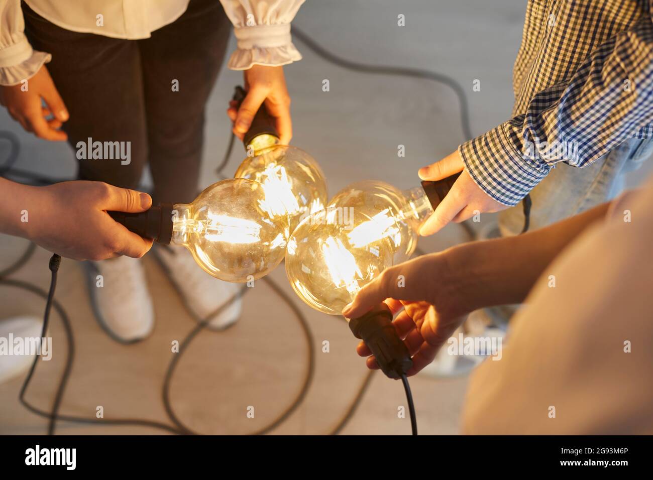 Gros plan de l'ampoule lumineuse dans les mains des enfants et des enseignants qui signifie une nouvelle idée. Banque D'Images