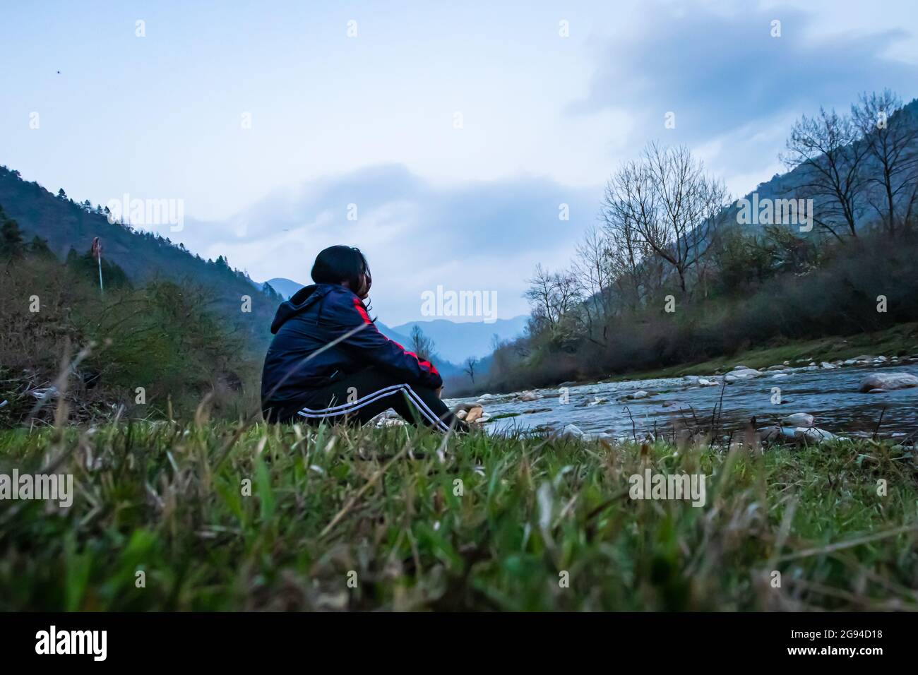 une jeune fille assise près d'un ruisseau d'eau avec un fond de montagne le matin, image est prise au shergaon arunachal pradesh inde. Banque D'Images