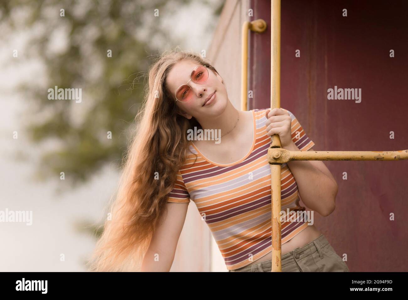 Rétro hippie teen fille dans des verres de couleur rose sur le train caboose Banque D'Images