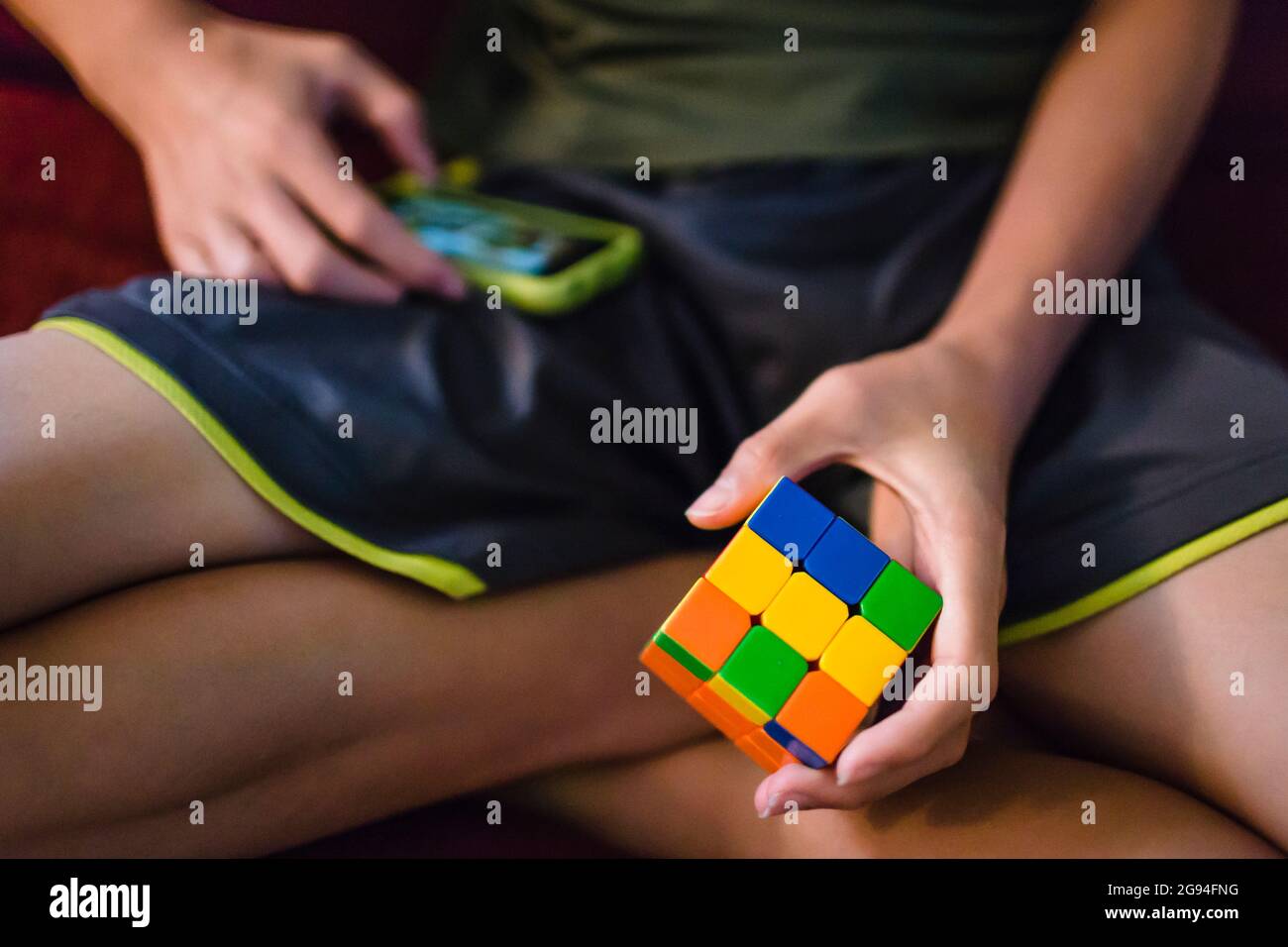 Un jeune adolescent asiatique joue avec un cube de casse-tête et un téléphone Banque D'Images