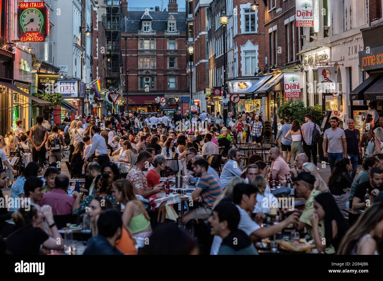Les personnes qui mangent sur des tables de restaurant placées à l'extérieur sur Frith Street à Soho, Londres, Royaume-Uni Banque D'Images