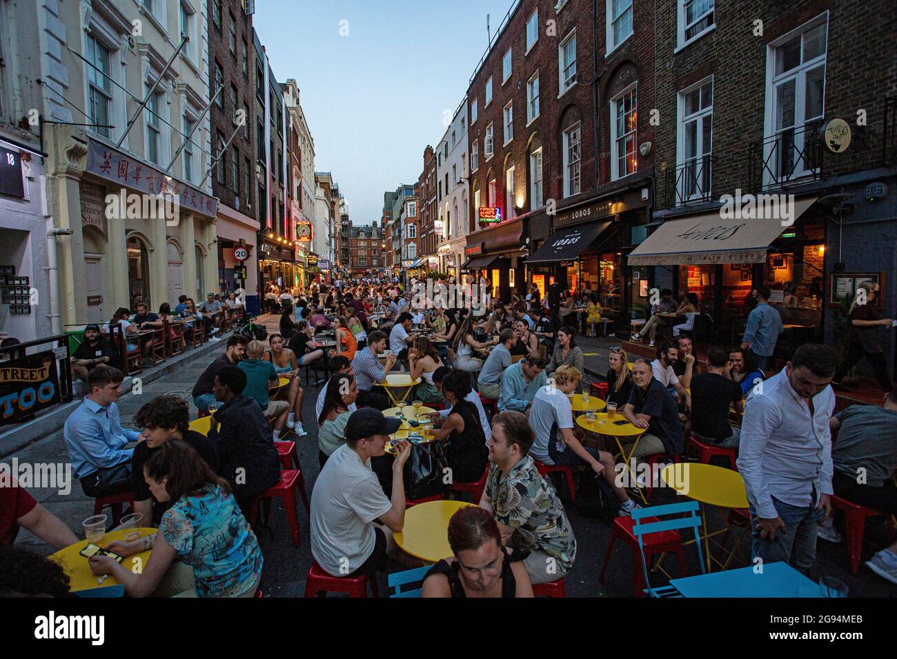 Les gens qui mangent sur des tables de restaurant placées à l'extérieur de Frith Street, Soho, Londres, Royaume-Uni. Banque D'Images