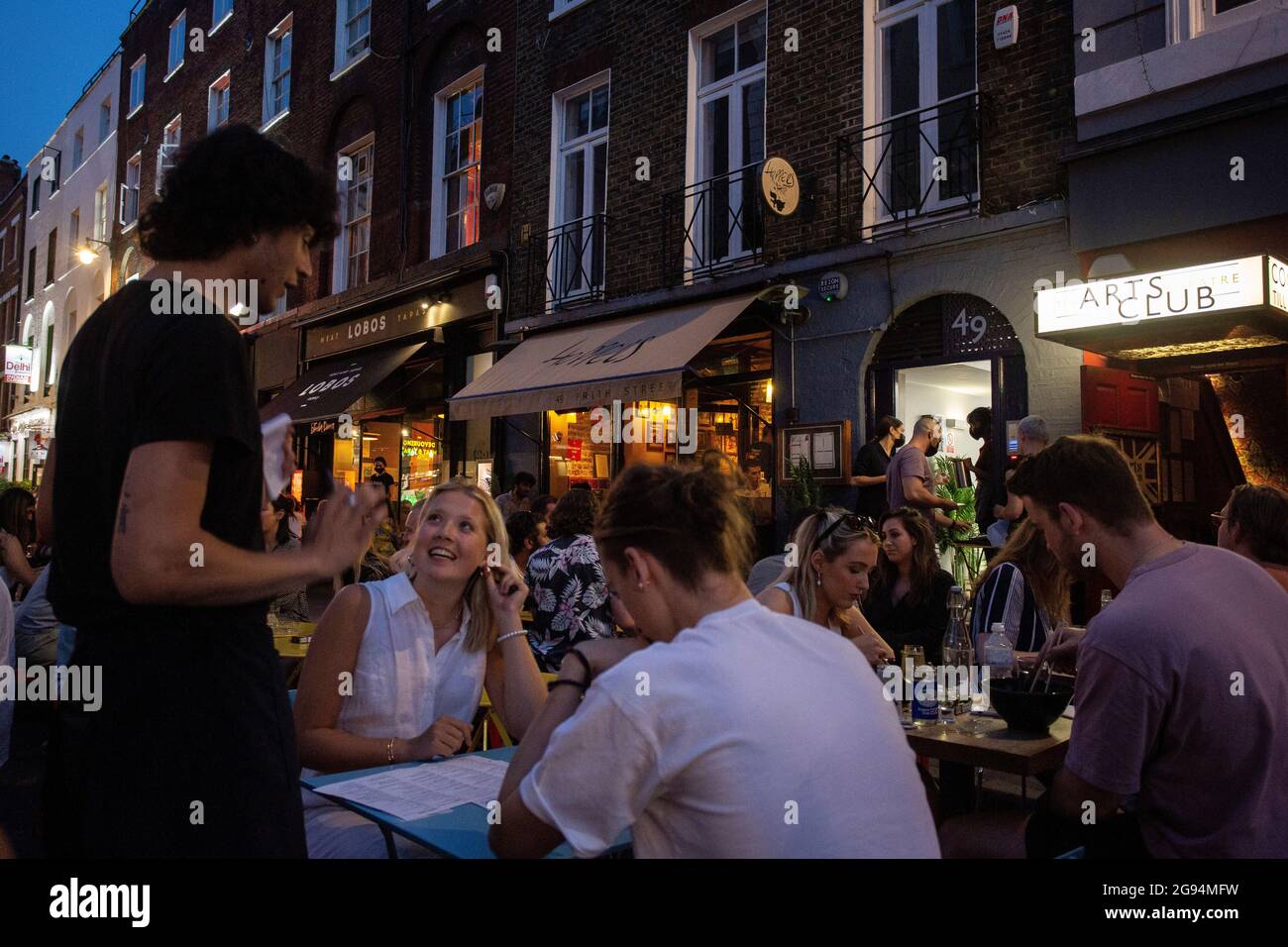 Les personnes qui boivent et mangent sur des tables placées à l'extérieur de Frith Street à Soho, Londres, le 23 juillet 2021 Banque D'Images