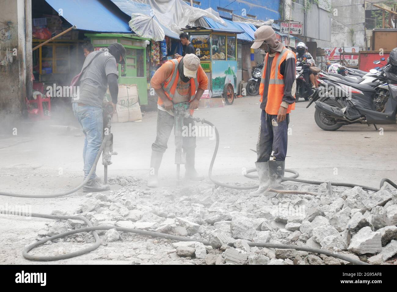 Les ouvriers de la construction utilisent des outils de marteau-piqueur pour détruire le béton de rue. Banque D'Images