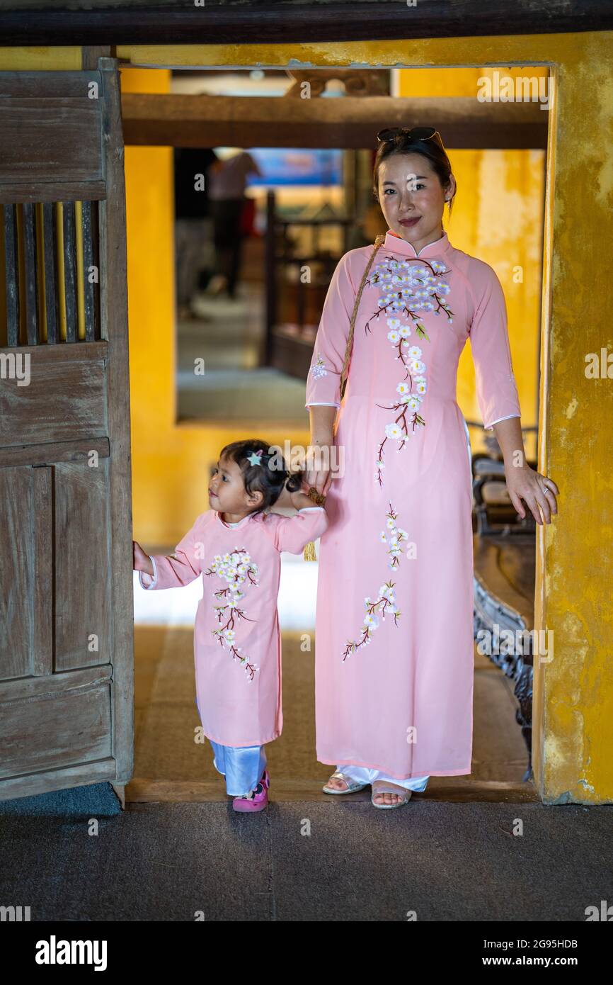 Jeune maman asiatique vêtue de vêtements similaires avec sa fille passant du temps avec elle pendant des vacances Banque D'Images