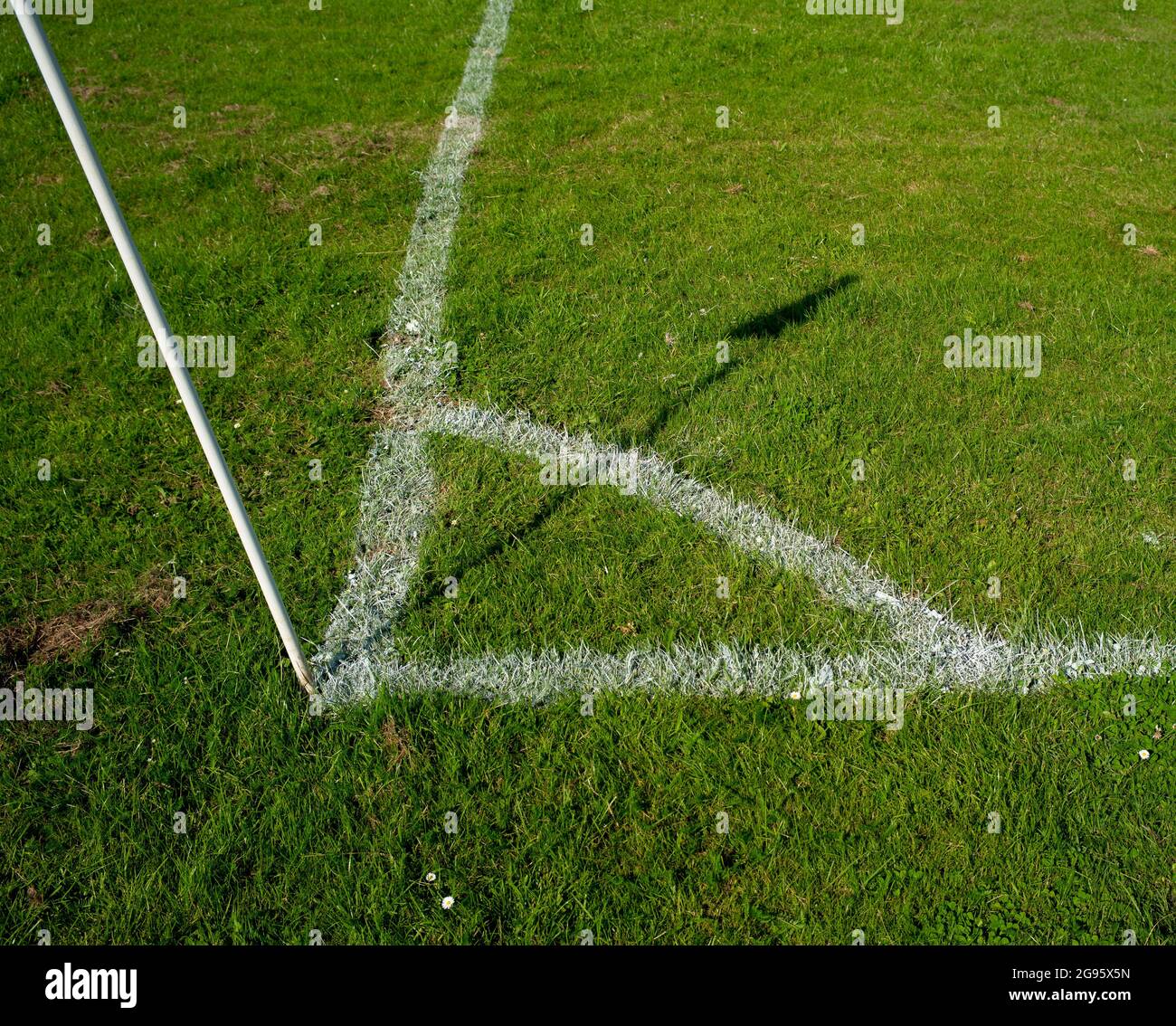 Un magnifique terrain de football amateur en gros plan sur la zone des coups de pied d'angle récemment peint et marqué avec l'ombre du drapeau d'angle du soleil. Banque D'Images